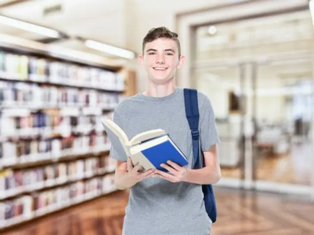 8th grader boy holding a book