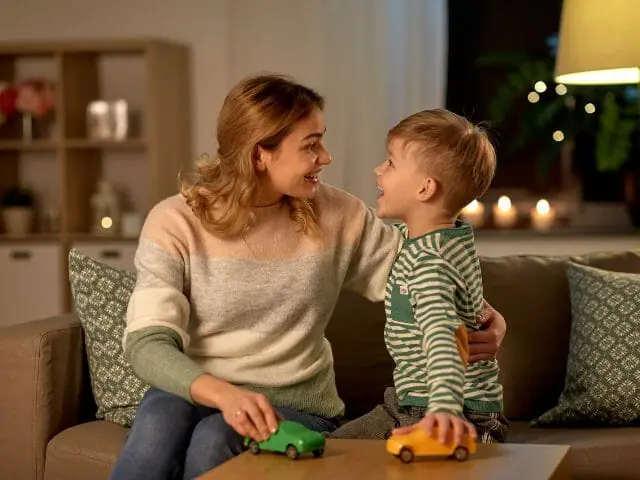 happy mother and son playing toy cars at home