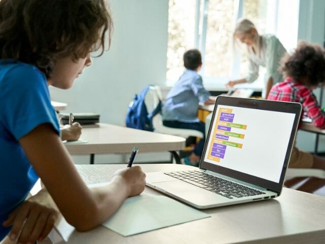 student reading on laptop holding pen