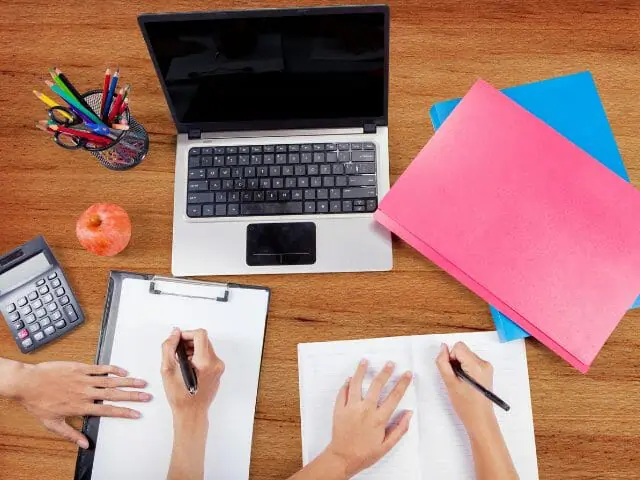 students writing in front of a laptop