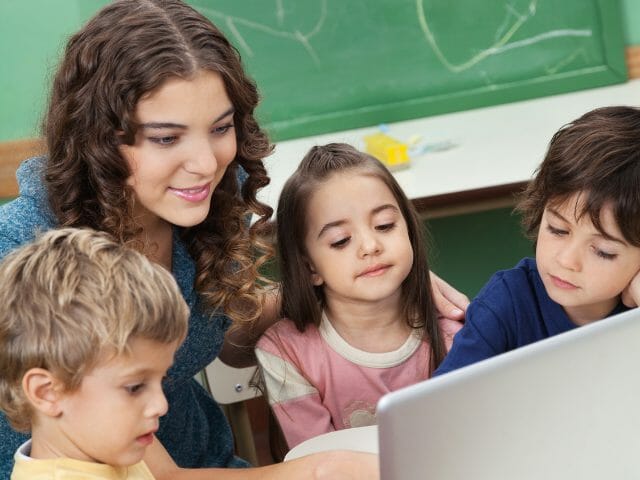 teacher with kids using laptop