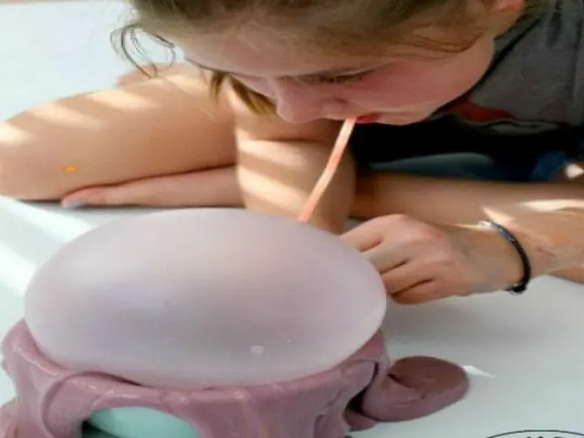 girl blowing bubble with slime