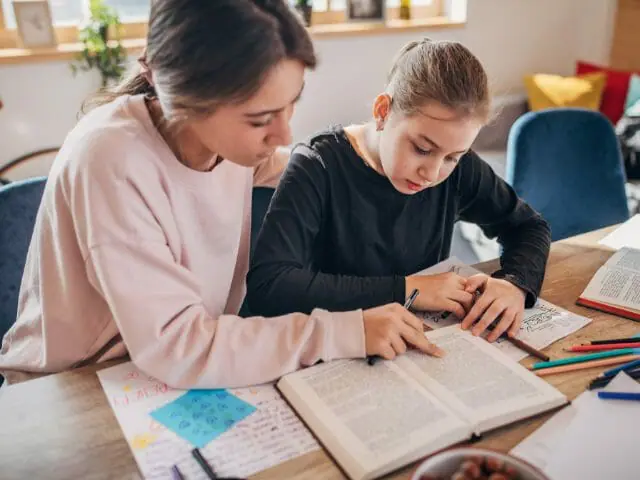 teacher and a student with book in classroom